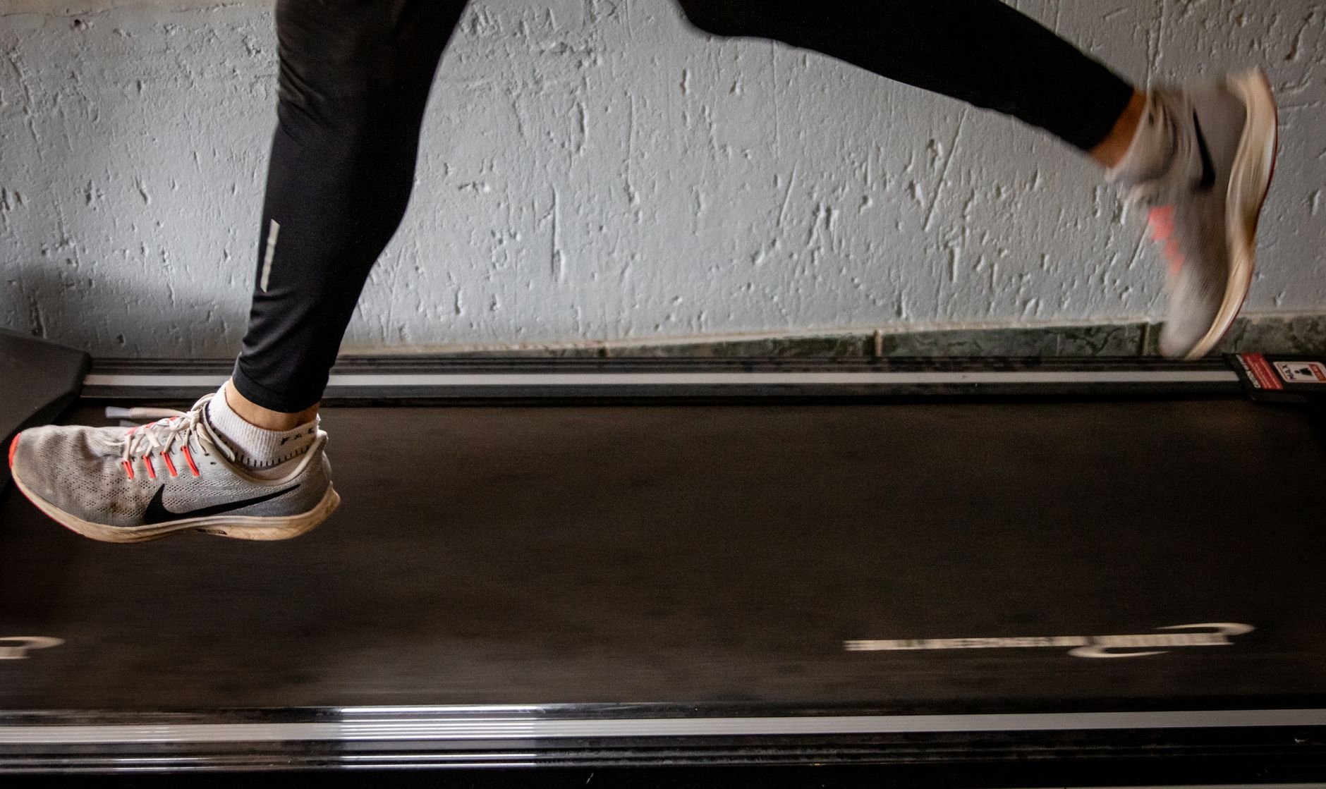 Close-up of a woman's legs running on a treadmill indoors.